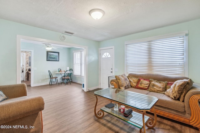 living room featuring ceiling fan, a textured ceiling, and hardwood / wood-style flooring