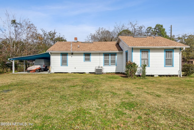 rear view of property featuring a lawn, central AC, and a carport