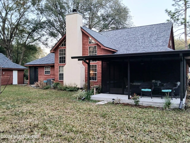 back of property with a shingled roof, cooling unit, a chimney, a yard, and a patio area