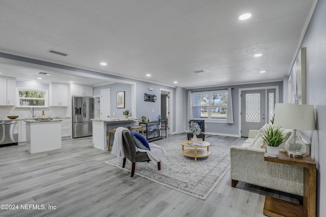 living room with crown molding, plenty of natural light, and light hardwood / wood-style floors