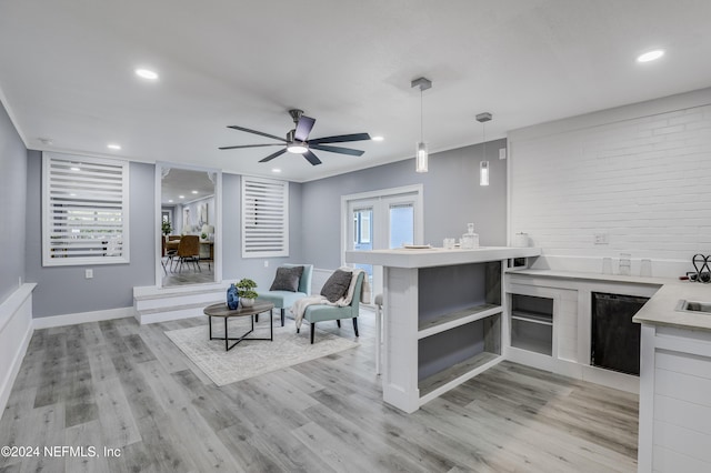 kitchen with kitchen peninsula, ceiling fan, light hardwood / wood-style flooring, and pendant lighting