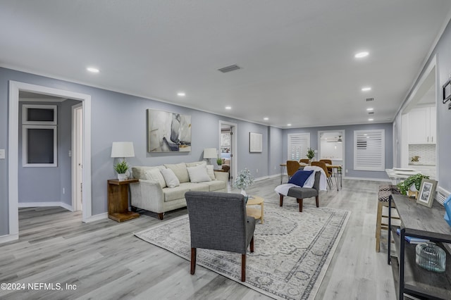 living room featuring crown molding and light hardwood / wood-style floors