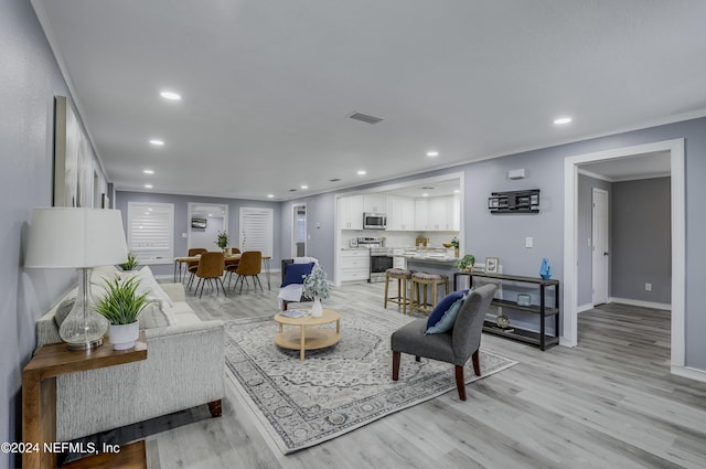 living room with light hardwood / wood-style floors and ornamental molding