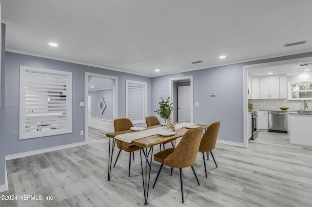 dining room with light hardwood / wood-style floors, sink, and crown molding