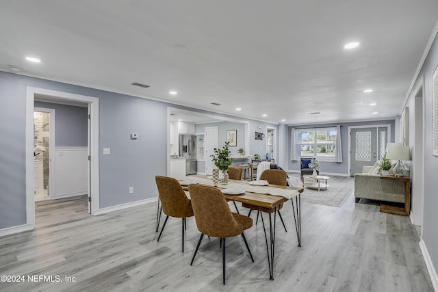 dining area with light wood-type flooring and ornamental molding