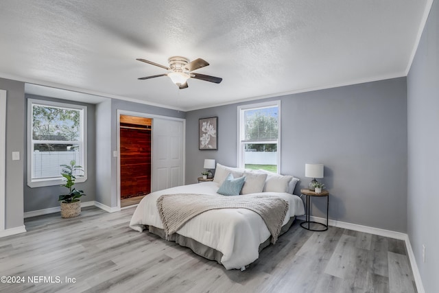 bedroom with multiple windows, a closet, ceiling fan, and ornamental molding