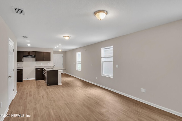 kitchen featuring light wood-type flooring, dark brown cabinets, a center island, and a breakfast bar area