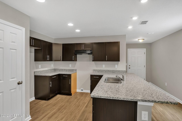 kitchen featuring sink, light stone counters, light hardwood / wood-style flooring, kitchen peninsula, and dark brown cabinets