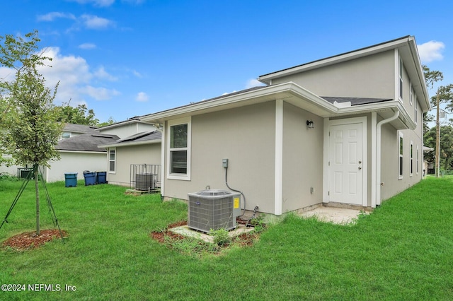 back of property with a yard and central AC