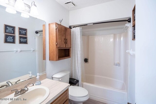 full bathroom featuring vanity, shower / bath combo, a textured ceiling, and toilet