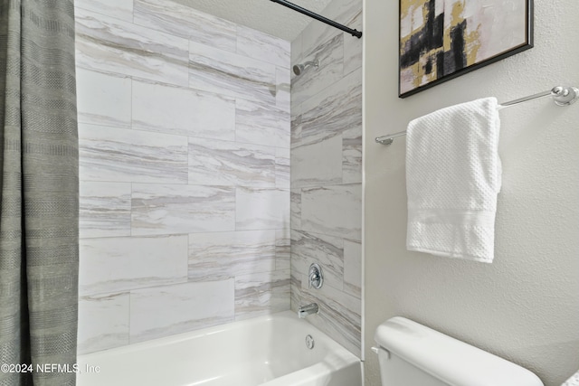 bathroom featuring tiled shower / bath combo and toilet