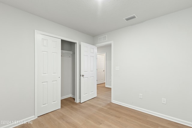 unfurnished bedroom with light hardwood / wood-style flooring and a closet