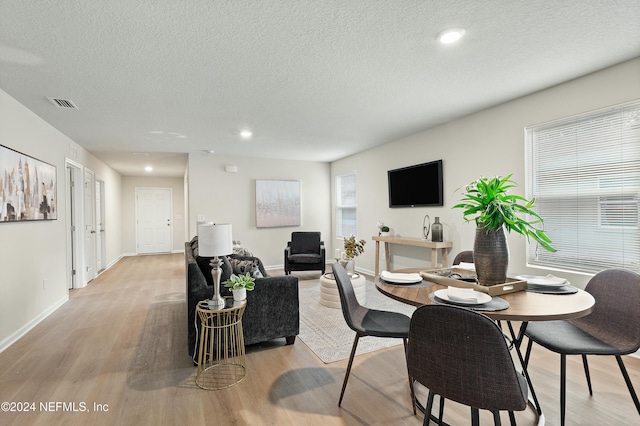 dining room with a textured ceiling and light hardwood / wood-style flooring