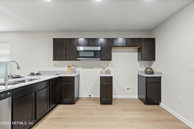 kitchen with dark brown cabinetry, light stone countertops, dishwasher, sink, and light wood-type flooring