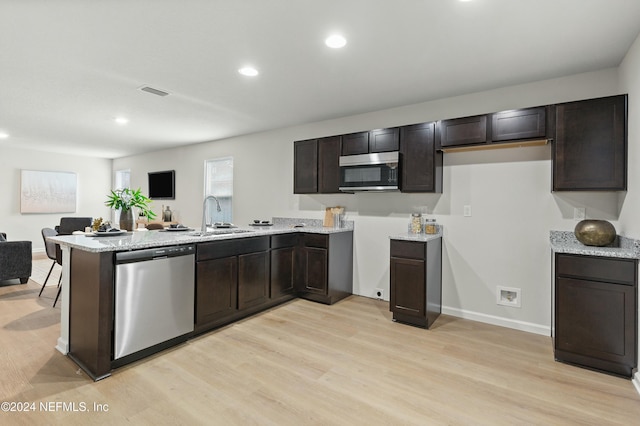 kitchen featuring sink, stainless steel dishwasher, dark brown cabinetry, light hardwood / wood-style floors, and kitchen peninsula