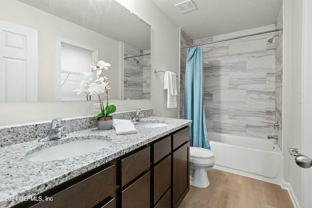 full bathroom featuring shower / bath combo, vanity, toilet, a textured ceiling, and wood-type flooring