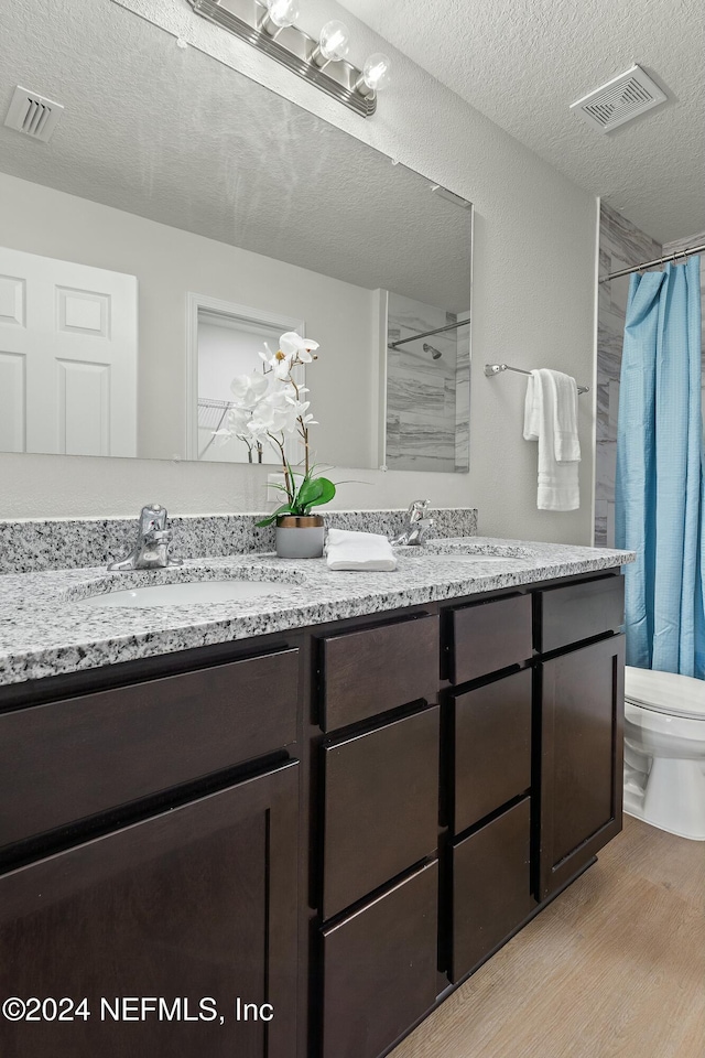 bathroom featuring hardwood / wood-style floors, vanity, toilet, a textured ceiling, and walk in shower