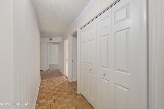 hallway with a textured ceiling, light parquet floors, and crown molding