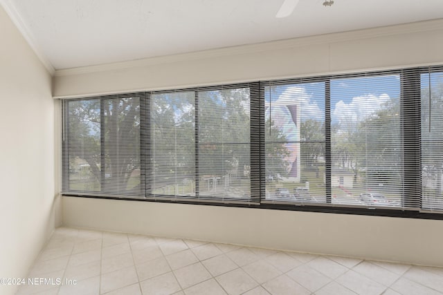 spare room with ceiling fan, light tile patterned floors, crown molding, and a wealth of natural light