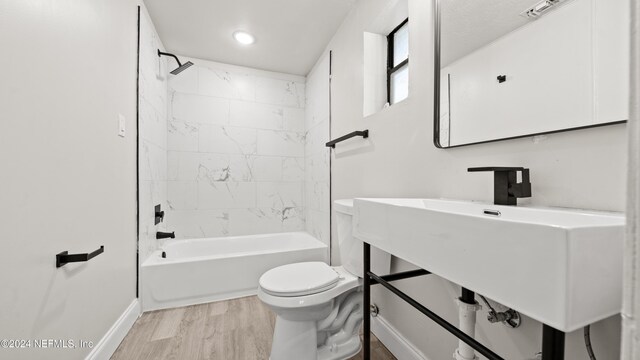 bathroom with wood-type flooring, tiled shower / bath combo, and toilet