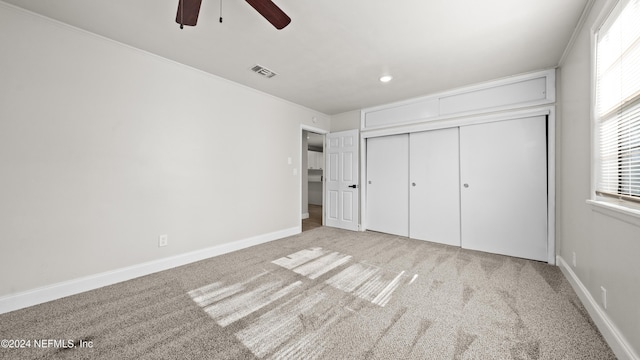 unfurnished bedroom with ceiling fan, light carpet, and a closet