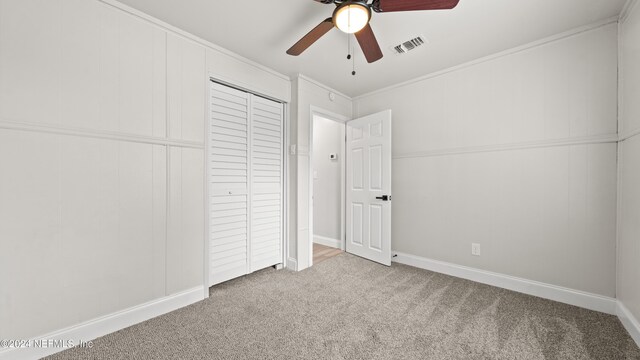 unfurnished bedroom with carpet, a closet, ceiling fan, and crown molding