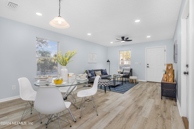 dining space with ceiling fan, light hardwood / wood-style floors, and a textured ceiling