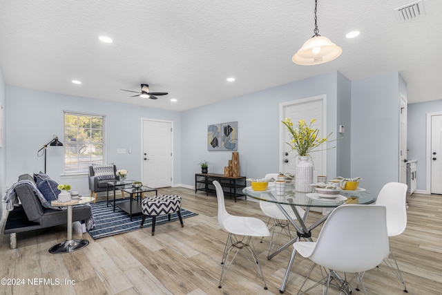 dining area with a textured ceiling, light hardwood / wood-style flooring, and ceiling fan