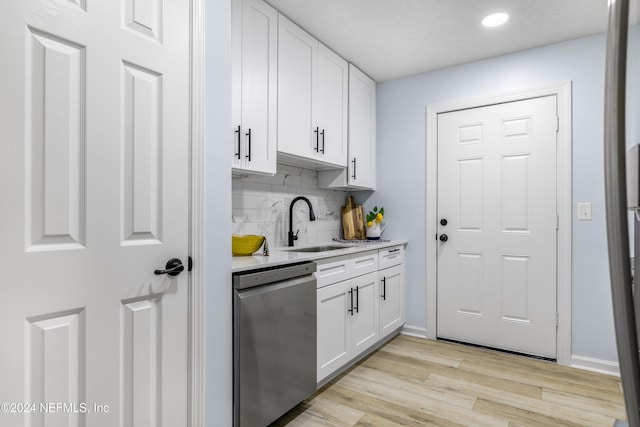 kitchen featuring dishwasher, sink, tasteful backsplash, light hardwood / wood-style floors, and white cabinets