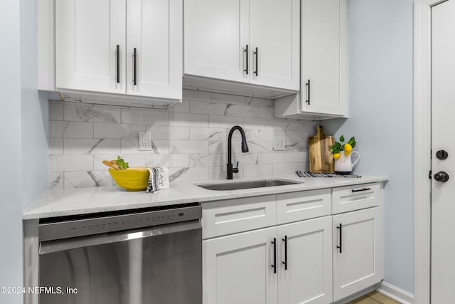 kitchen with decorative backsplash, light stone countertops, stainless steel dishwasher, sink, and white cabinets