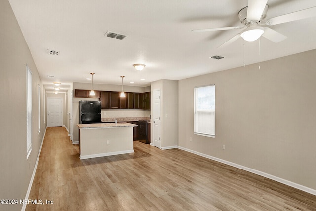 kitchen featuring black refrigerator, dark brown cabinetry, ceiling fan, a center island, and hanging light fixtures