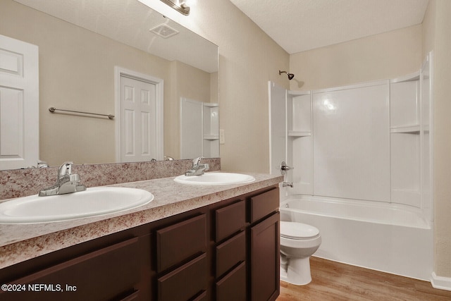 full bathroom featuring vanity, shower / washtub combination, toilet, a textured ceiling, and wood-type flooring