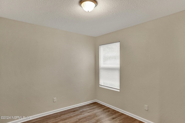 unfurnished room featuring hardwood / wood-style flooring, a textured ceiling, and a wealth of natural light