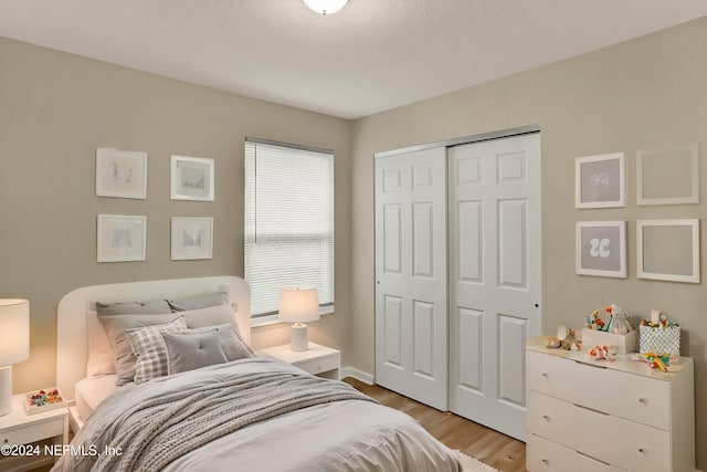 bedroom with light hardwood / wood-style floors and a closet