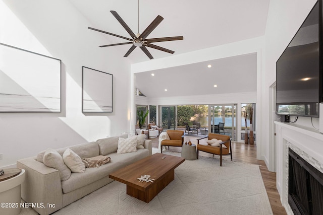 living room with ceiling fan, high vaulted ceiling, and light hardwood / wood-style floors