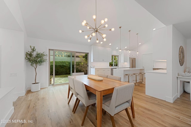 dining space featuring high vaulted ceiling, a chandelier, and light hardwood / wood-style floors