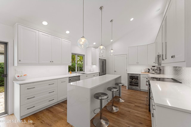 kitchen with wine cooler, white cabinetry, a kitchen bar, and a kitchen island