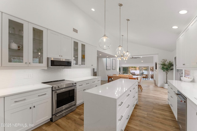 kitchen featuring white cabinetry, appliances with stainless steel finishes, a center island, and decorative light fixtures