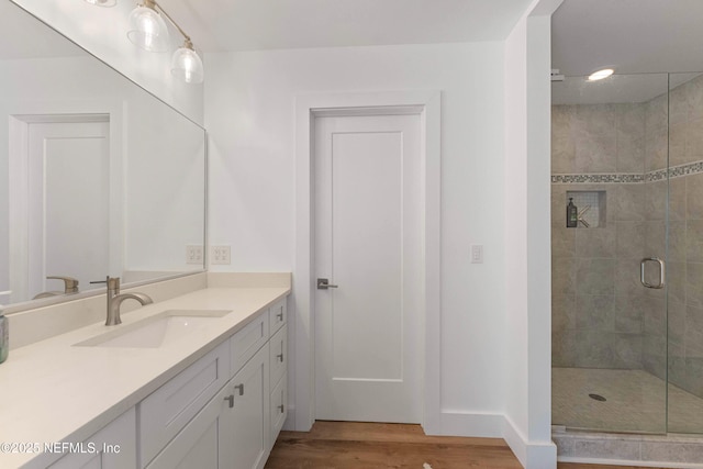 bathroom with hardwood / wood-style flooring, vanity, and a shower with door