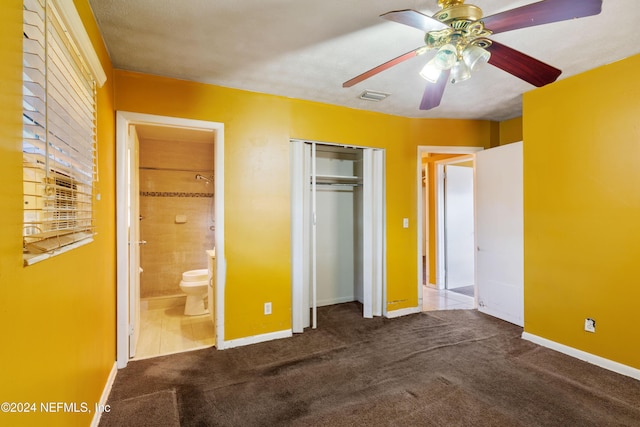 unfurnished bedroom featuring connected bathroom, ceiling fan, a closet, and dark colored carpet