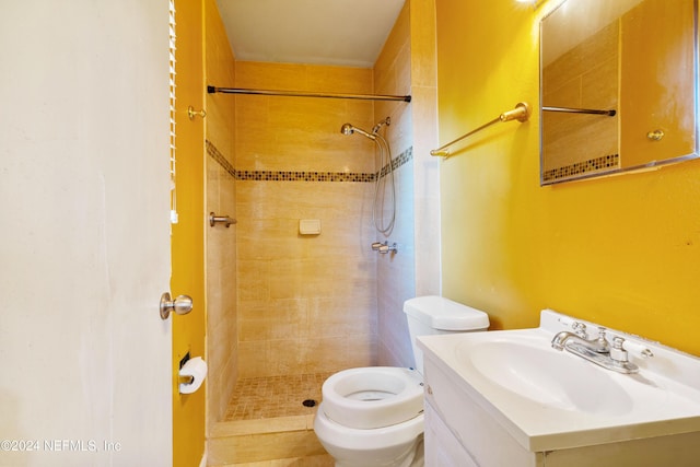 bathroom with tiled shower, vanity, and toilet