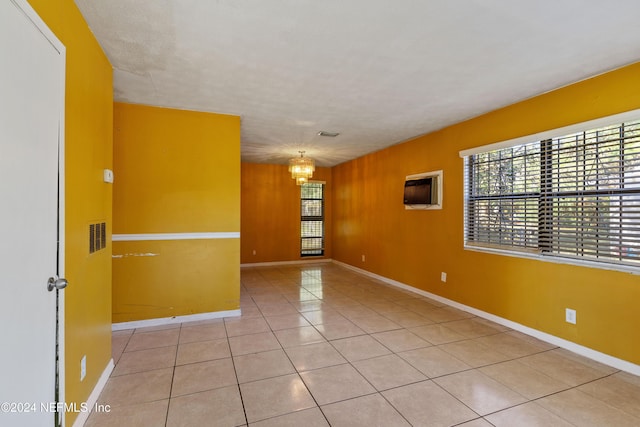 tiled empty room featuring an inviting chandelier