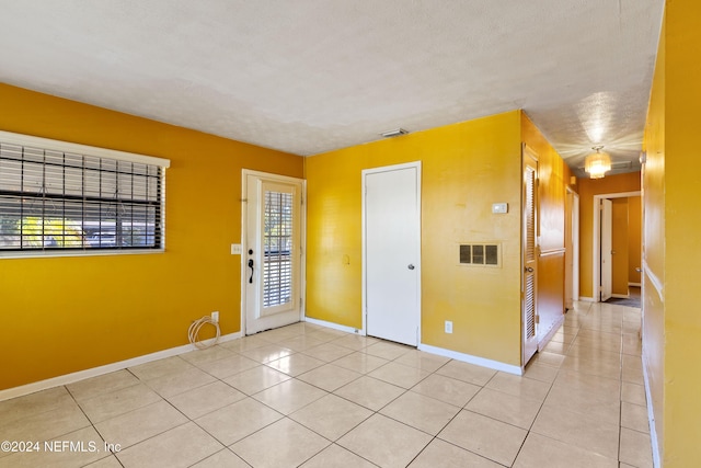 tiled empty room featuring a textured ceiling