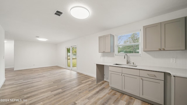 kitchen featuring light hardwood / wood-style floors, plenty of natural light, gray cabinetry, and sink