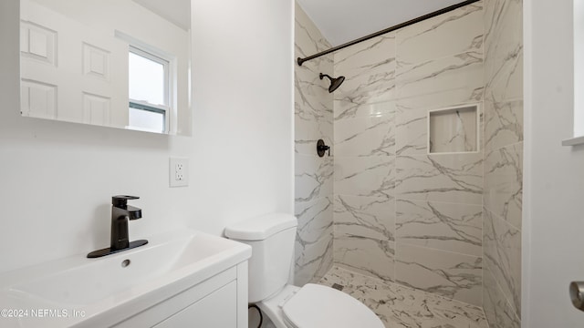 bathroom featuring toilet, vanity, and tiled shower