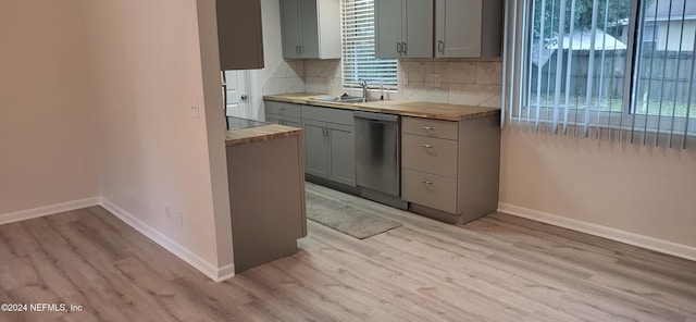 kitchen with stainless steel dishwasher, butcher block countertops, light wood-type flooring, and sink