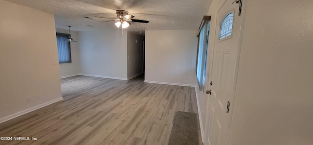 unfurnished room with a textured ceiling, light hardwood / wood-style floors, and ceiling fan