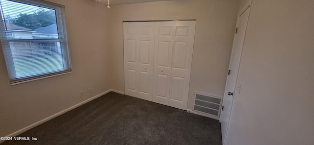 unfurnished bedroom featuring dark carpet and a closet