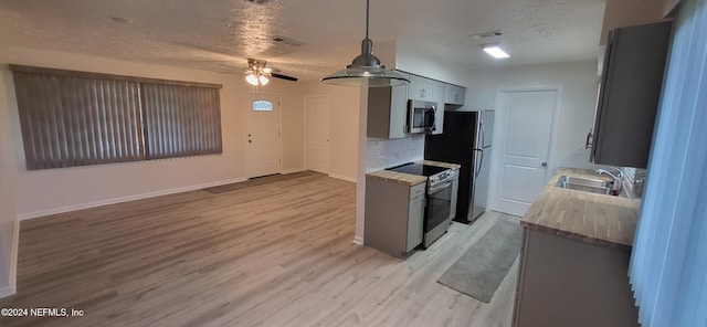 kitchen with sink, tasteful backsplash, light hardwood / wood-style floors, a textured ceiling, and appliances with stainless steel finishes