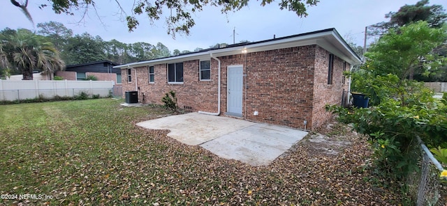 back of property with cooling unit, a patio area, and a lawn